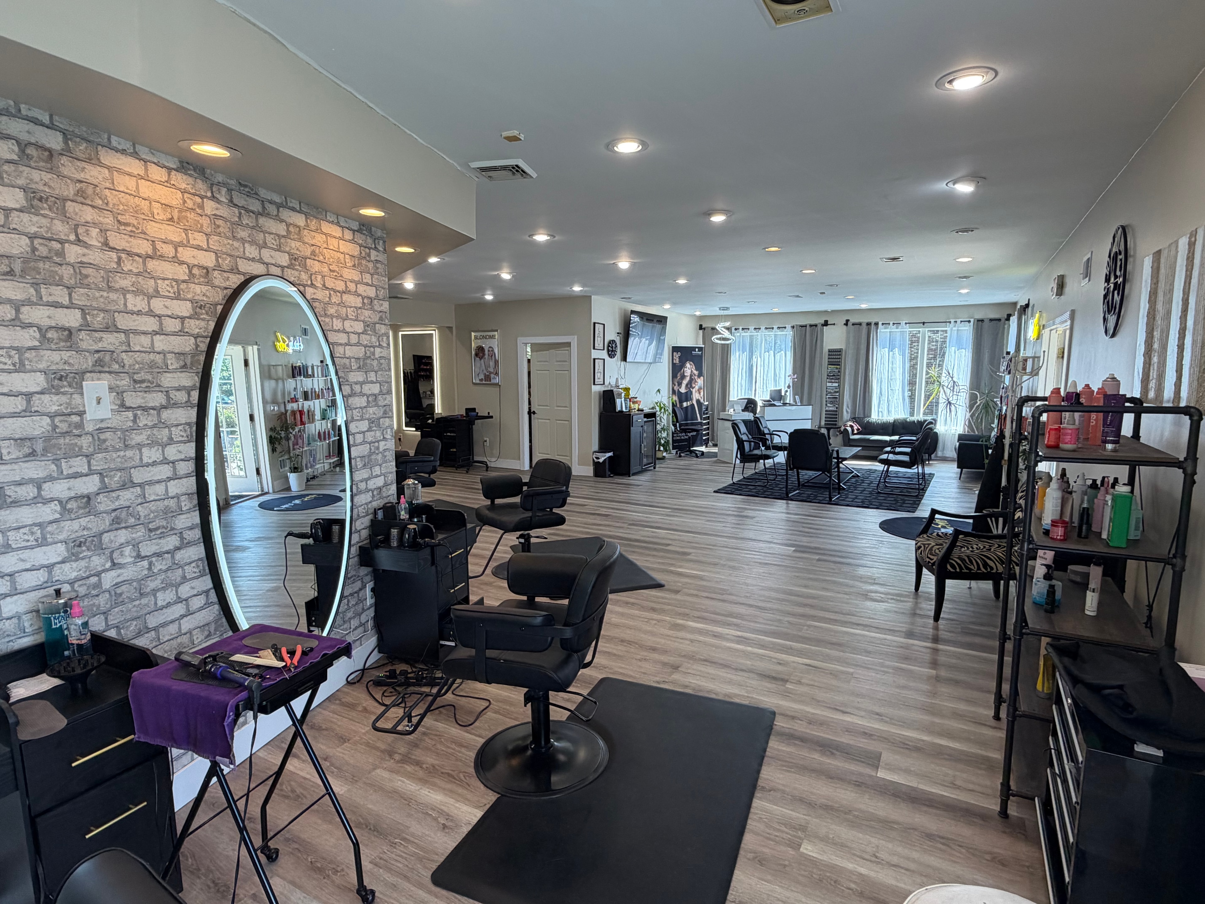 Hair by Sebo styling floor with brick accent wall and oval mirror